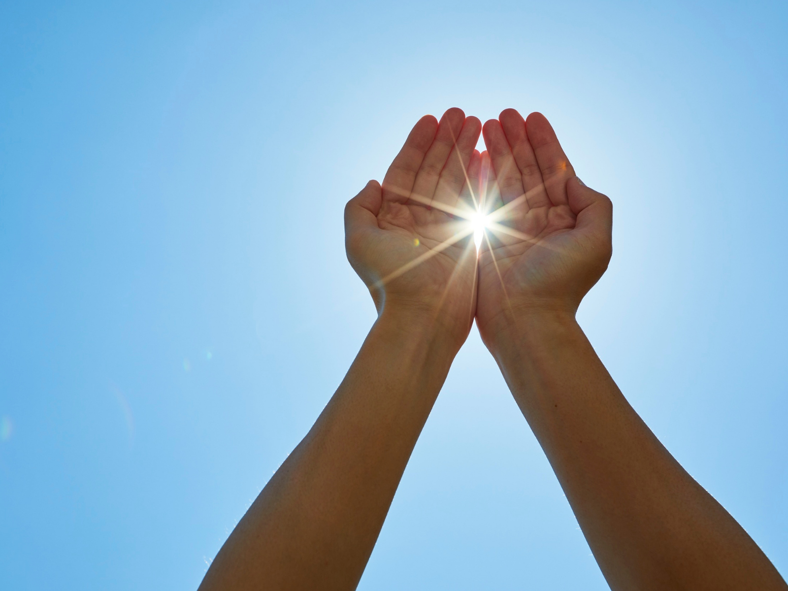 Hands raised toward sunlight, symbolizing hope and patient-led action.
